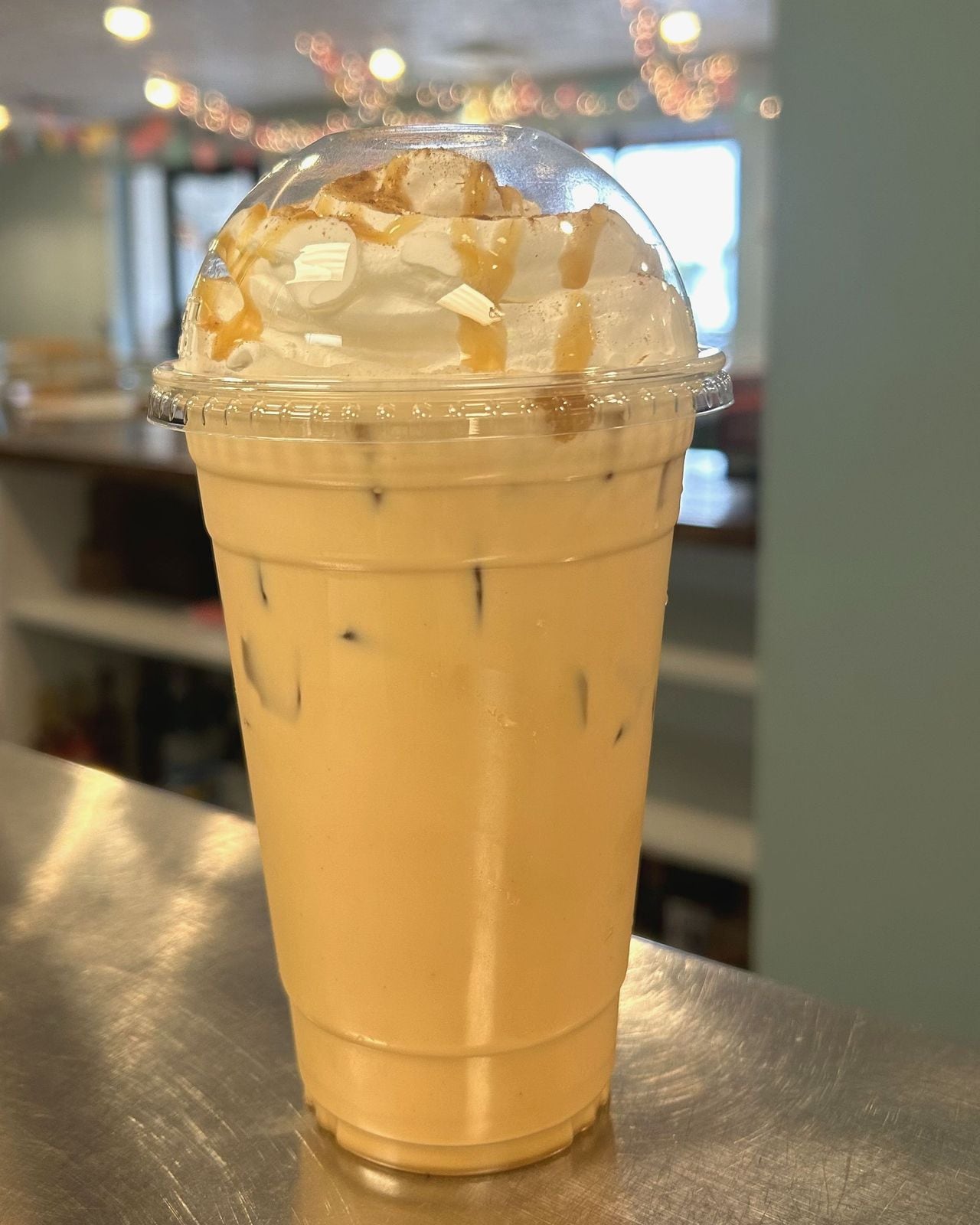 Iced latte topped with whipped cream and caramel drizzle
